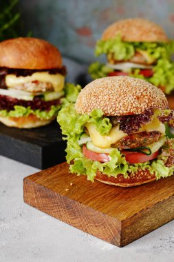 Büyük hamburger bir pirzola, sebze ve taze ekmek ile. Sandviç kahvaltı için. Fast food. Atıştıracak bir şeyler ahşap bir gemide hizmet.