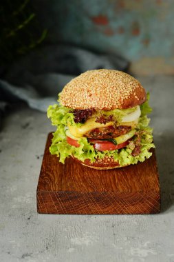 Büyük hamburger bir pirzola, sebze ve taze ekmek ile. Sandviç kahvaltı için. Fast food. Atıştıracak bir şeyler ahşap bir gemide hizmet.
