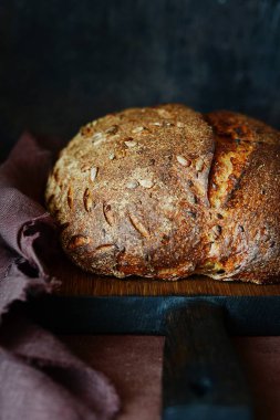 Karanlık bir arka plan üzerinde taze ev yapımı ekmek. Çavdar unu ile keten ve Ayçiçeği tohumları ekmek. Mayasız ekmek. Öğle yemeği zamanı.