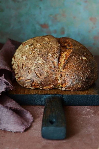 Fresh homemade bread on a dark background. Bread on rye flour with seeds of flax and sunflower. Unleavened bread. Lunch time.