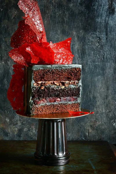 Extravagant cake of black color with bright red caramel decor. Glamorous birthday cake