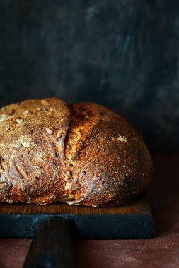 Karanlık bir arka plan üzerinde taze ev yapımı ekmek. Çavdar unu ile keten ve Ayçiçeği tohumları ekmek. Mayasız ekmek. Öğle yemeği zamanı.