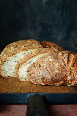 Karanlık bir arka plan üzerinde taze ev yapımı ekmek. Çavdar unu ile keten ve Ayçiçeği tohumları ekmek. Mayasız ekmek. Öğle yemeği zamanı.