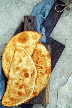 Özbek Doğu Tatar mutfağı, et ve suluguni peynir ve Yeşiller ahşap oyun tahtası ile cheburek. Cheburek - et ve soğan ile kızarmış pasta. Çok sayıda Türk ve Moğol geleneksel çanak. Empanada 