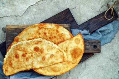 Özbek Doğu Tatar mutfağı, et ve suluguni peynir ve Yeşiller ahşap oyun tahtası ile cheburek. Cheburek - et ve soğan ile kızarmış pasta. Çok sayıda Türk ve Moğol geleneksel çanak. Empanada 