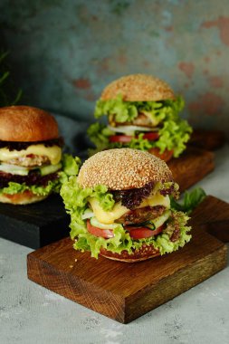 Büyük ev yapımı sulu biftek Burger, sebze ve taze bir ekmek. Sandviç kahvaltı için. Fast food. Atıştıracak bir şeyler ahşap bir gemide hizmet. Ev yapımı Hamburger Close-up