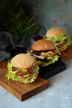 Büyük ev yapımı sulu biftek Burger, sebze ve taze bir ekmek. Sandviç kahvaltı için. Fast food. Atıştıracak bir şeyler ahşap bir gemide hizmet. Ev yapımı Hamburger Close-up