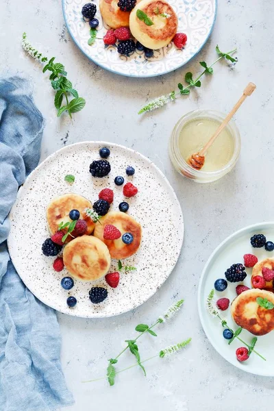  Pazar kahvaltısı peynirli kek, bal, taze meyveler ve nane ile. Krep peynir veya lor börek bal ve çilek plaka mavi masa üstü görünümünde dekore edilmiştir. Sağlıklı ve diyet kahvaltı.