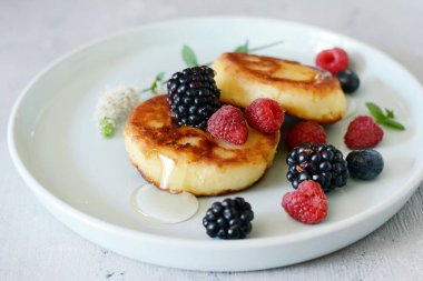 Pazar kahvaltısı peynirli kek, bal, taze meyveler ve nane ile. Krep peynir veya lor börek bal ve çilek plaka mavi masa üstü görünümünde dekore edilmiştir. Sağlıklı ve diyet kahvaltı.