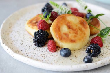 Pazar kahvaltısı peynirli kek, bal, taze meyveler ve nane ile. Krep peynir veya lor börek bal ve çilek plaka mavi masa üstü görünümünde dekore edilmiştir. Sağlıklı ve diyet kahvaltı.