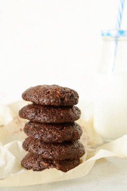 Yuvarlak çikolata bisküvi ve bir şişe süt hafif bir arka plan üzerinde pişmiş. Çikolatalı kek