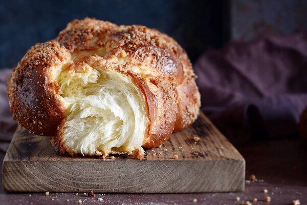 Challah or Hala is a traditional jewish sweet fresh sabbath bread loaf,  fresh bun on cutting board. Brioche bread on breakfast table. The golden glaze of these baked brioche buns boasts 