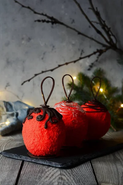 Sweet cake made in the form of New Year\'s decoration. Ball. Delicious unusual dessert for the Christmas table. Cake with mousse, berry jelly, biscuit in chocolate icing