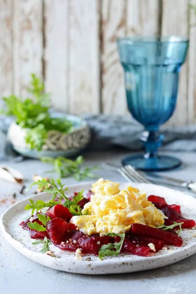Cevizli pancar, aromatik otlar ve roka karışımıyla çırpılmış yumurta. Lezzetli sağlıklı kahvaltı. Beyaz tabakta soslu pancar carpaccio..
