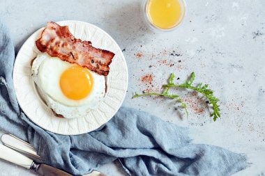 Tabak kızarmış yumurta, pastırma ve gri arka plan üzerinde çavdar ekmeği tost ile kahvaltı. İngiliz kahvaltısı, portakal suyu