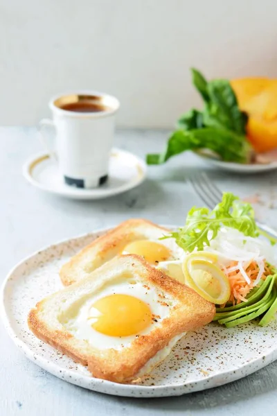 American breakfast on a plate with fried eggs in toast, with tomatoes, fresh daikon, carrots, arugula and espresso. Fried egg for traditional breakfast close up shoot