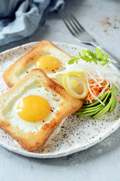 American breakfast on a plate with fried eggs in toast, with tomatoes, fresh daikon, carrots, arugula and espresso. Fried egg for traditional breakfast close up shoot