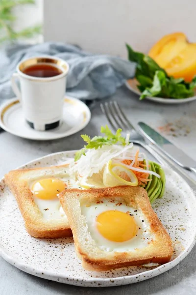 American breakfast on a plate with fried eggs in toast, with tomatoes, fresh daikon, carrots, arugula and espresso. Fried egg for traditional breakfast close up shoot