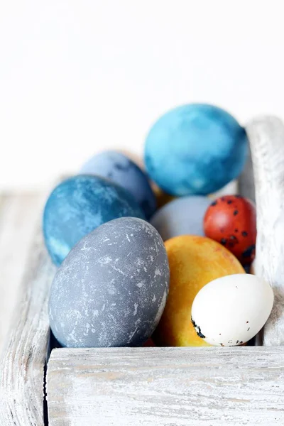 Colored Easter eggs in a wooden basket on a white background. Happy easter. Easter decoration.