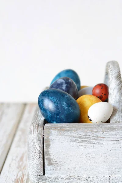 Colored Easter eggs in a wooden basket on a white background. Happy easter. Easter decoration.
