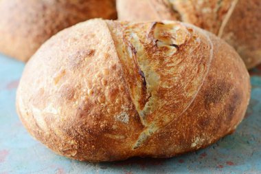 Gri-mavi arka plan, taze ev yapımı ekmek kepekli un üzerinde keten tohumu ile. Fransız ekmeği yuvarlak şekli. Ekmek pişirme. Mayasız ekmek