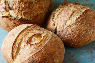 Gri-mavi arka plan, taze ev yapımı ekmek kepekli un üzerinde keten tohumu ile. Fransız ekmeği yuvarlak şekli. Ekmek pişirme. Mayasız ekmek