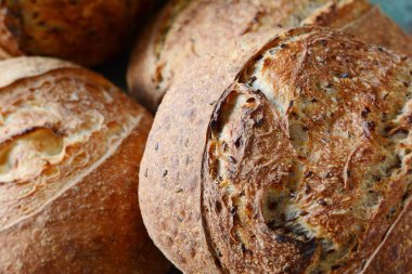 Gri-mavi arka plan, taze ev yapımı ekmek kepekli un üzerinde keten tohumu ile. Fransız ekmeği yuvarlak şekli. Ekmek pişirme. Mayasız ekmek