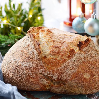 Taze ev yapımı ekmek kepekli un üzerinde gri-mavi bir arka plan üzerinde. Fransız ekmeği yuvarlak şekli. Ekmek pişirme. Mayasız ekmek. Noel ve yeni yıl