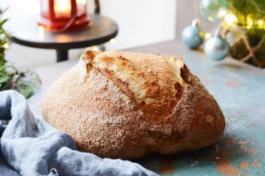 Taze ev yapımı ekmek kepekli un üzerinde gri-mavi bir arka plan üzerinde. Fransız ekmeği yuvarlak şekli. Ekmek pişirme. Mayasız ekmek. Noel ve yeni yıl