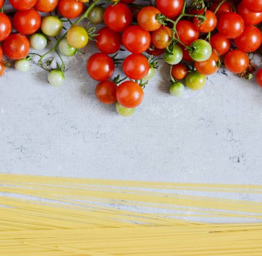 Gıda çerçeve. Makarna malzemeler kavramı. Pişmemiş makarna ve kiraz domates mavi bir arka plan üzerinde. Üstten görünüm kopya alanı ile. Italyan Mutfagi