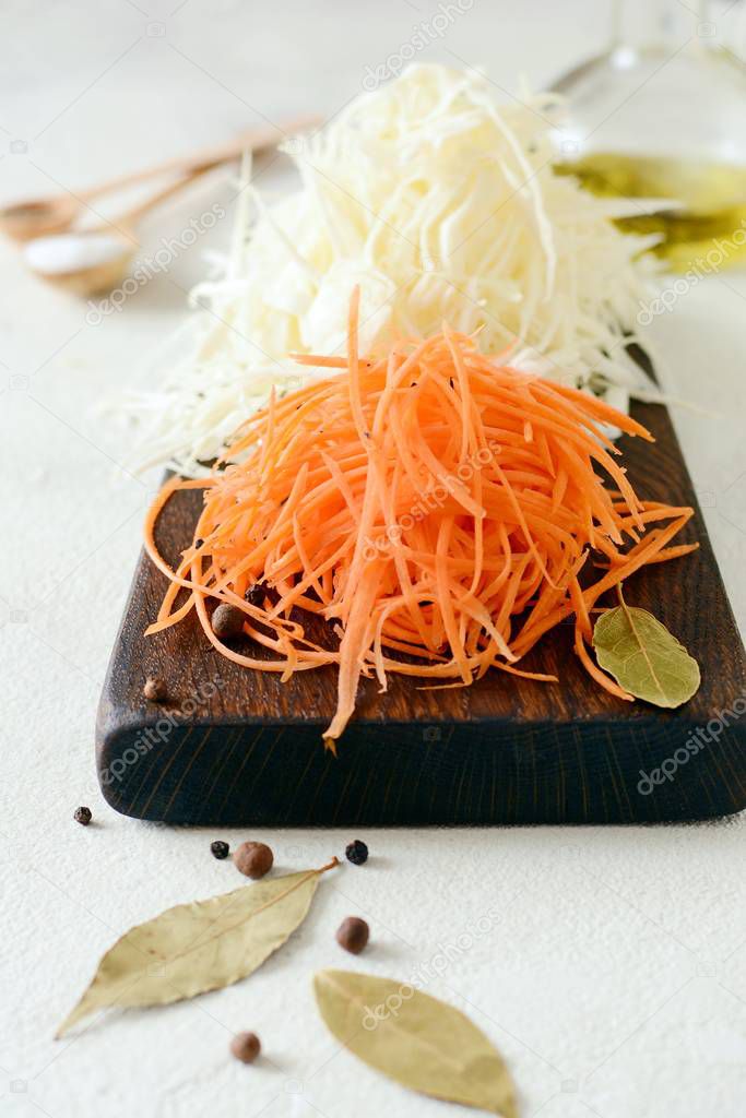Slicing Fresh cabbage and carrots on a wooden board on a light background. Vegetables for ferment, for long fermentation. Assortment of fresh vegetables. Healthy food conception. Top view,shredded