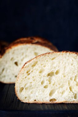 Taze ev yapımı ekmek kepekli un üzerinde karanlık bir arka plan üzerinde. Fransız ekmeği yuvarlak şekli. Ekmek pişirme. Mayasız ekmek