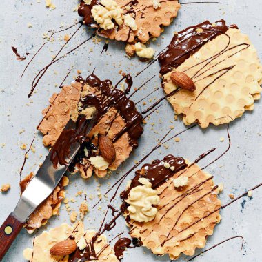 Tuzlu karamelli Hollanda gözlemeleri, tuzlu karamel ile Hollanda gözlemeleri, fındık ve gri arka planda siyah çikolata. Lezzetli çıtır tatlı. Düz yatıyordu