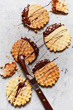 Tuzlu karamelli Hollanda gözlemeleri, tuzlu karamel ile Hollanda gözlemeleri, fındık ve gri arka planda siyah çikolata. Lezzetli çıtır tatlı. Düz yatıyordu