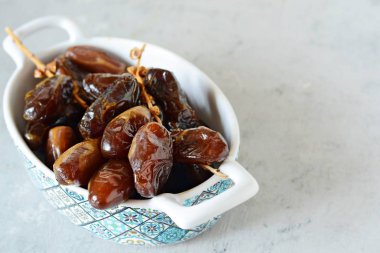 Gri-mavi arkaplanda sulu tarihli bir kase. Sağlıklı ve lezzetli yemekler. Çiğ Organik Medjool Tarihleri 