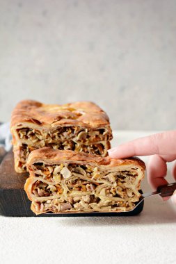 Gri arka planda et ve mantarlı gözleme turtası. Ekmek şeklinde krep. Slav mutfağı. Gri arka planda etli ve mantarlı gözleme turtası, kopyalama alanı. Shrovetide Maslenitsa