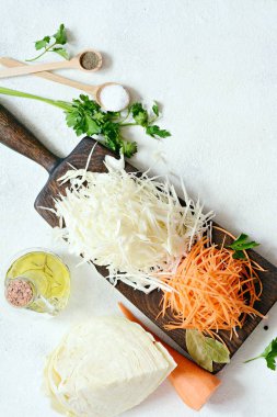 Taze lahana ve havuç hafif bir arka plan üzerinde ahşap bir gemide dilimleme. Maya, uzun fermantasyon için sebze. Taze sebze ürün yelpazesine. Sağlıklı gıda anlayışı. Üstten görünüm, rendelenmiş