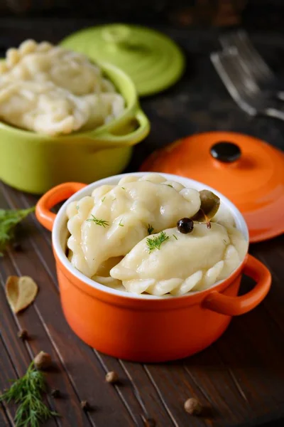 Köfte Patates otlar, baharatlar ve karanlık bir arka plan üzerinde bir seramik bölümü tencerede tereyağı ile. Varenyky, vareniki, pierogi, pyrohy - köfte dolgulu.