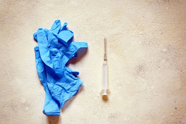 Blue medical gloves and a medical syringe on a light textured background. Vaccination items, shots, Copy space
