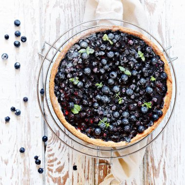 Antika ahşap zemin üzerine üzümlü Tart. Krem peynir ve beyaz vintage arka planda, gurme Fransız tatlı taze yaban mersini ile tart.