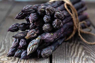 Ahşap arka planda bir demet taze kuşkonmaz.