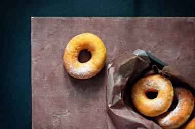 Kahverengi arka planda şeker kremalı klasik taze çörekler..