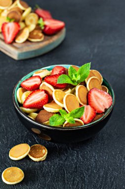 Koyu arkaplanda çilek ve nane şekeri bulunan minik krepli şık ev kahvaltısı. Yemek Geçmişi. Mini mısır gevreği krepleri..