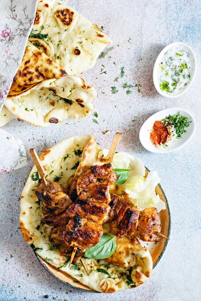 Grilled chicken kebabs (chicken skewers) with herbed garlic butter naan tortillas and Greek tzatziki sauce. Delicious street food.