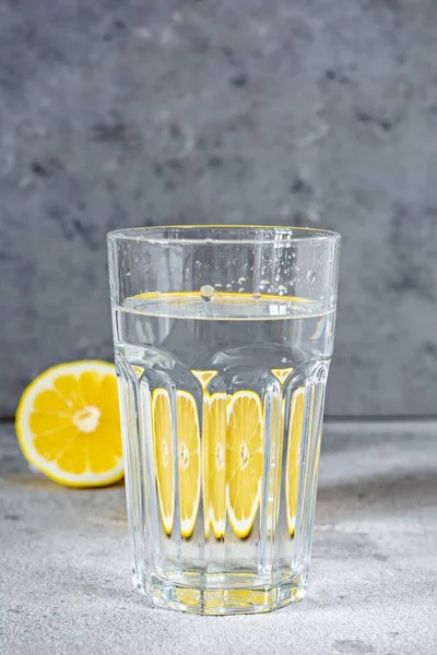 Shooting through glass objects with water. Orange (lemon) reflecting through a glass cup with water on a gray background.