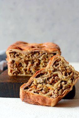 Gri arka planda et ve mantarlı gözleme turtası. Ekmek şeklinde krep. Slav mutfağı. Gri arka planda etli ve mantarlı gözleme turtası, kopyalama alanı. Shrovetide Maslenitsa