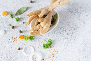 Tavuk kemikleri (tavuk ayağı), sebzeler, baharatlar ve gri arka planda çorba için bitkiler. Hayvan kaynaklı doğal kolajen..