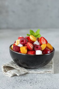 Siyah kasede taze meyve salatası. Sağlıklı organik yiyecekler, düşük kalorili tatlı. Vegan kavramı