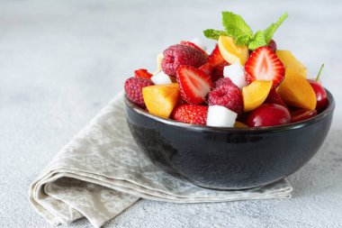 Siyah kasede taze meyve salatası. Sağlıklı organik yiyecekler, düşük kalorili tatlı. Vegan kavramı