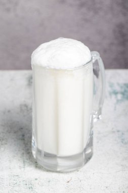 Köpüklü tereyağı. Yakın plan. Gri arka planda bir bardak ayran.